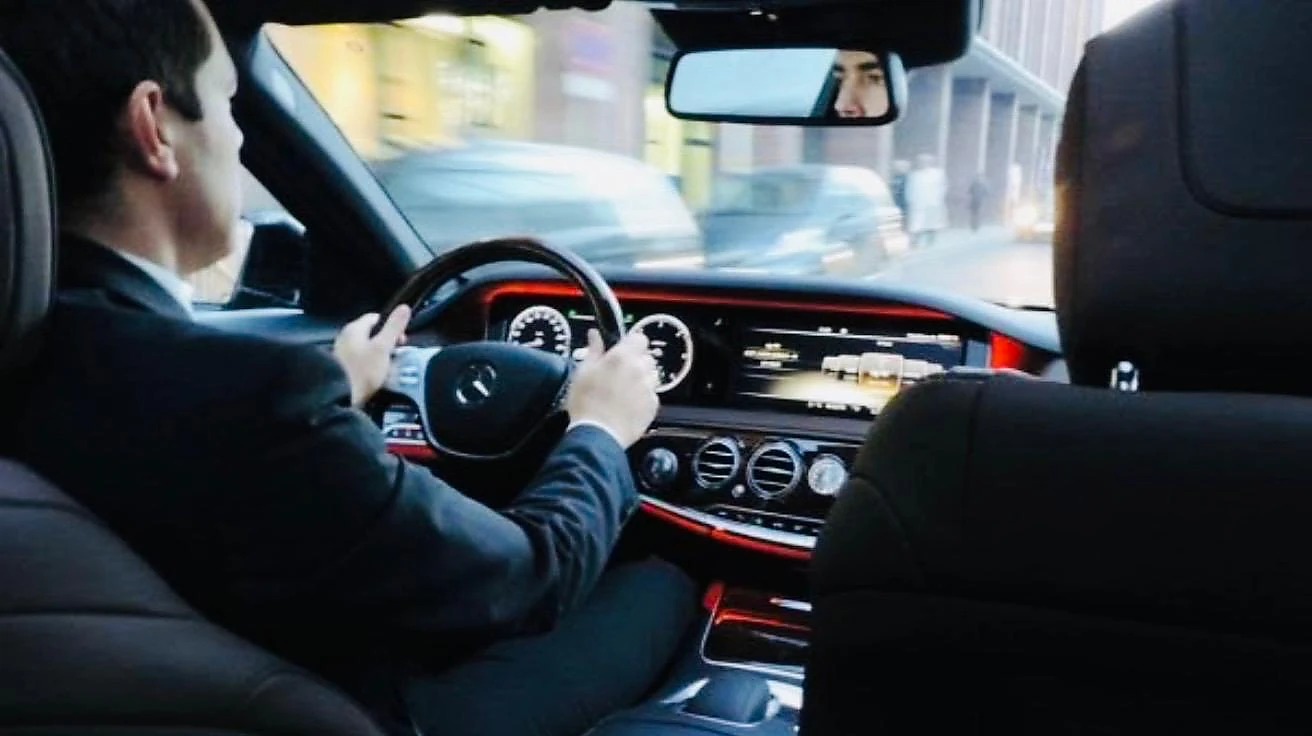 Chauffeur en costume au volant d’une berline